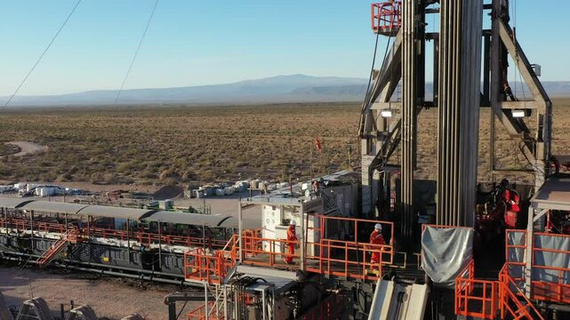 Drone films Vaca Muerta workers working inside the drilling rig. In the background you can see the Auca Mahuida volcano