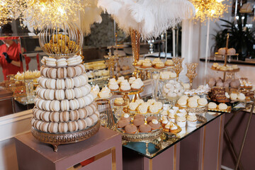A table full of desserts including macaroons, cupcakes, and other sweets. The table is set up for a party or event