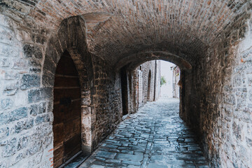 Obraz premium A narrow stone tunnel with a door on the left side in Gubbio Italy Umbria