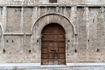 Fototapeta premium A brown door with a white arch above it in Gubbio Italy Umbria