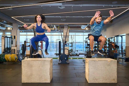 Fitness enthusiasts performing box jumps in gym