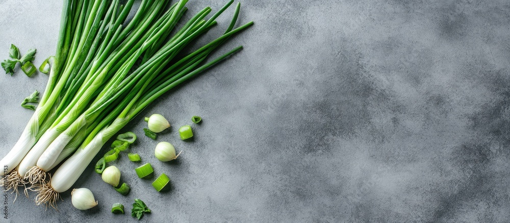 Poster Freshly chopped green spring onions and their stems on a textured grey table with a clear space for text on the right side of the image.