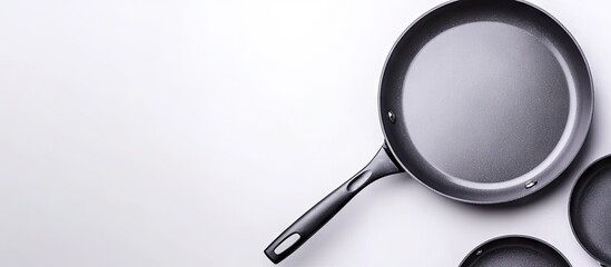 Fototapeta premium Gray frying pan with black handle positioned on light gray surface with subtle gradient against a clean white background showcasing cookware.