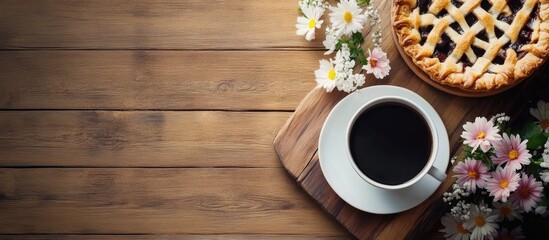 Coffee cup and pie surrounded by daisies on a rustic wooden surface, top view showcasing warm brown tones and vibrant white and yellow flowers.
