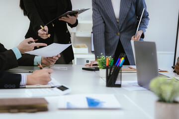 A team of professionals work together in an office to analyze financial charts, market strategies and work as a team to drive business growth and success.