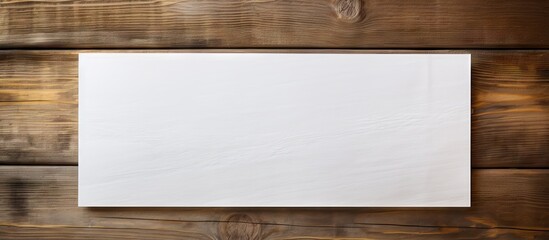 Naklejka premium Wooden background featuring a horizontal blank white paper centered for text input, warm brown tones enhancing rustic appeal.