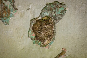 Close-up of a deteriorating wall with peeling paint, revealing multiple layers of old paint and...