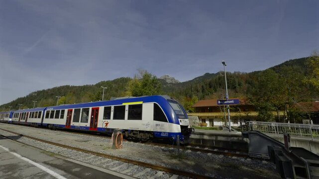 Bahnhof in Bayrischzell, Bayern, Deutschland. Train stands at its terminus against backdrop of mountains in Bavarian Alps in sunny fall weather. Public railway transportation in Southern Germany. 