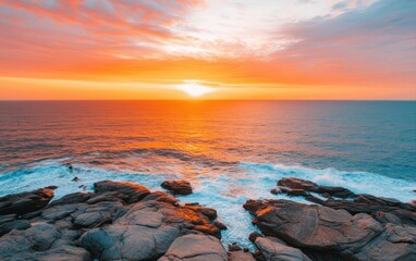 Obraz premium Tranquil Sunset Over Rocky Coastline with Vibrant Skies and Calm Ocean Waves