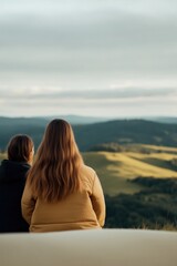 Fototapeta premium Two figures sit peacefully, gazing at expansive hills under sere