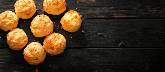 Freshly baked cheese scones arranged in a circular pattern on a rustic black wooden table showcasing golden hues and crumbly textures.