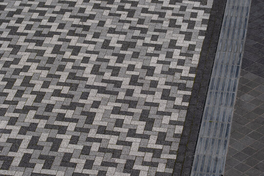 Urban paving with intricate herringbone tile pattern, contemporary public space.