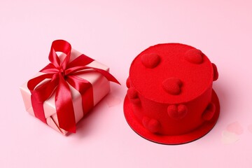 Beautiful red cake with hearts and gift box on a pink background