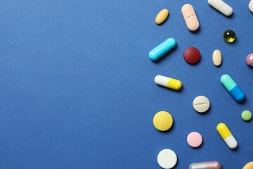 Various pills on blue background, top view