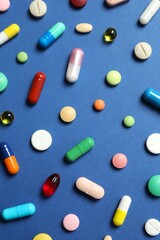 Various pills on blue background, top view