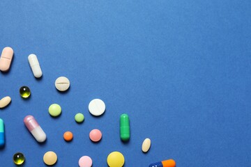Various pills on blue background, top view