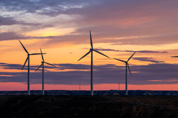 Wind turbines at sunset in Zaragoza, Spain, sustainable energy landscape with dramatic sky.