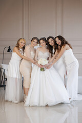 Naklejka premium A group of five women are posing for a picture in front of a wall. One of the women is wearing a white dress and holding a bouquet of flowers. Scene is cheerful and celebratory