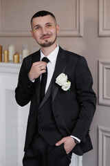 A man in a suit and tie is standing in front of a fireplace. He is wearing a white shirt and a...