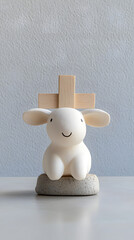Fototapeta premium Minimalist lamb figurine with wooden cross on neutral background
