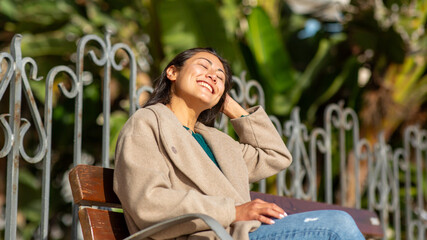 Latin woman enjoying the sunlight on a park bench