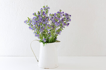Bouquet of wild flowers polemonium in a white vintage jug.