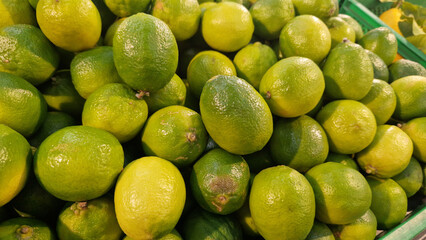 Limes close-up with selective focus. Heaps of tasty limes for sale in a store. Variety of fresh produce. Ripe limes for sale in a supermarket. Ripe, juicy, green fruits with vitamin C