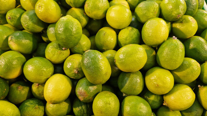 Limes close-up with selective focus. Heaps of tasty limes for sale in a store. Variety of fresh produce. Ripe limes for sale in a supermarket. Ripe, juicy, green fruits with vitamin C