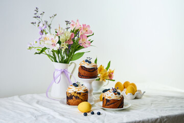 Traditional Easter cakes on festive table decorated with fresh flowers and colorful painted Easter eggs.