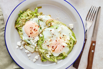 Breakfast with fried egg in zucchini noodles nest with feta cheese, healthy breakfast, top view, close up