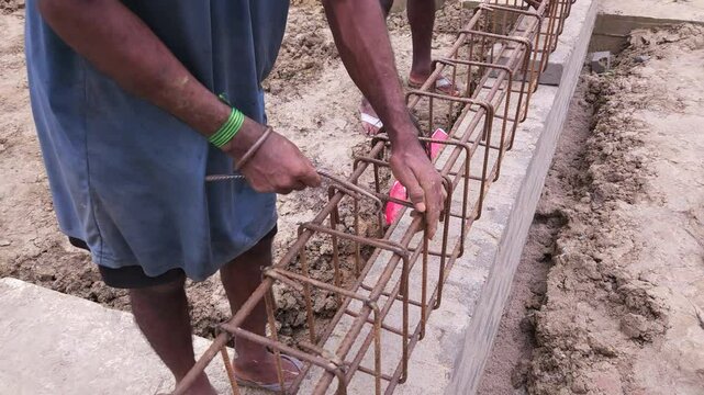 Construction workers using reinforced tmt steel bar with ease at the construction site, Reinforced bar (rebar). TMT steel rods tied together forming the core of concrete