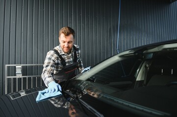Car detailing - the man holds the microfiber in hand and polishes the car. Selective focus