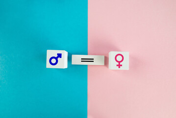Gender equality concept. Wooden cubes with male and female symbols on a colored  background.