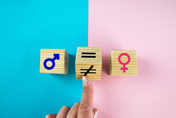 Gender equality symbol. Hand turns cube and changes inequality sign to equal sign between male and female symbols. Nice pink and blue background