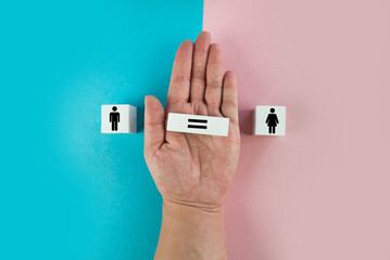 Gender equality symbol. Hand turns cube and changes inequality sign to equal sign between male and female symbols. Nice pink and blue background