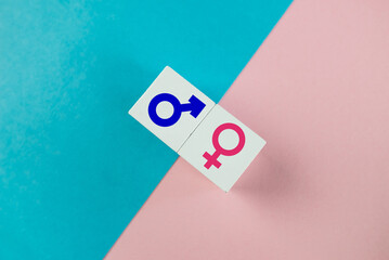 Gender equality concept. Wooden cubes with male and female symbols on a colored  background.