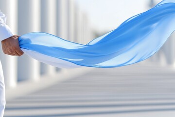 A person gracefully holding a flowing blue fabric in a bright setting