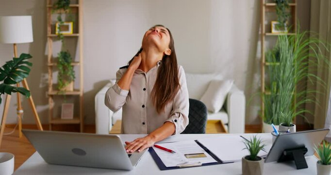 Businesswoman suffering neck pain while working from home office