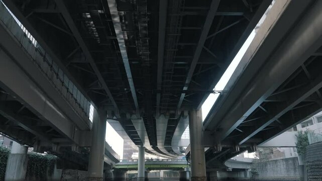 Underneath view of a massive bridge, highlighting its structural design, steel framework, and engineering details. Capturing urban infrastructure, construction, and architectural significance