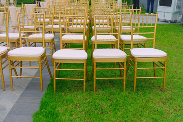 Chairs with gold frames arranged in neat rows for wedding ceremony celebration. Outdoor event setting at hotel rooftop.