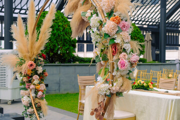 Beautiful outdoor wedding ceremony setting at a rooftop. Flower bouquet decorations on metal ring arch in front of table. Chic luxury wedding concept.