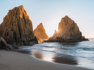 Golden hour light shining through rocky formations by the beach at sunset.