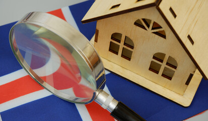 Wooden house model, magnifying glass and Icelandic flag on gray background. Find real estate in...