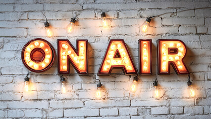 Backdrop of an illuminated “On Air” sign surrounded by light bulbs with a white brick wall.