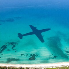 Naklejka premium flight shadow on a crystal blue sea, the big contrast between the flight emissions and the beauty of nature