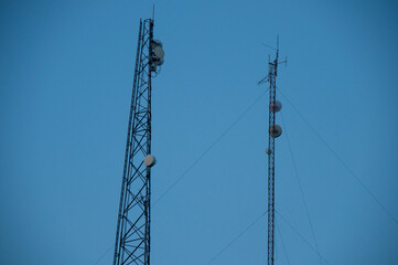Tall communication towers standing against a vivid blue sky, illustrating infrastructure and modern connectivity technology.