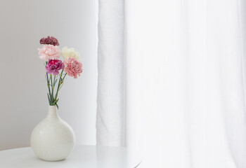 beautiful carnation flowers in ceramic vase on white table