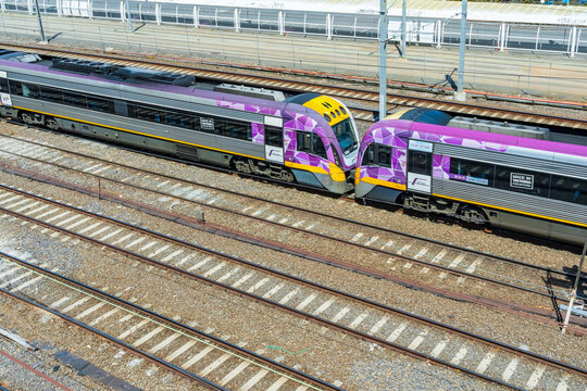 Two commuter trains end to end speeding through a railway yard