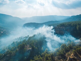 Obraz premium Hazy mountain landscape with sun rays breaking through atmospheric smoke