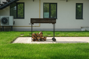 Barbecue with prepared firewood. Barbecue area near the cottage.